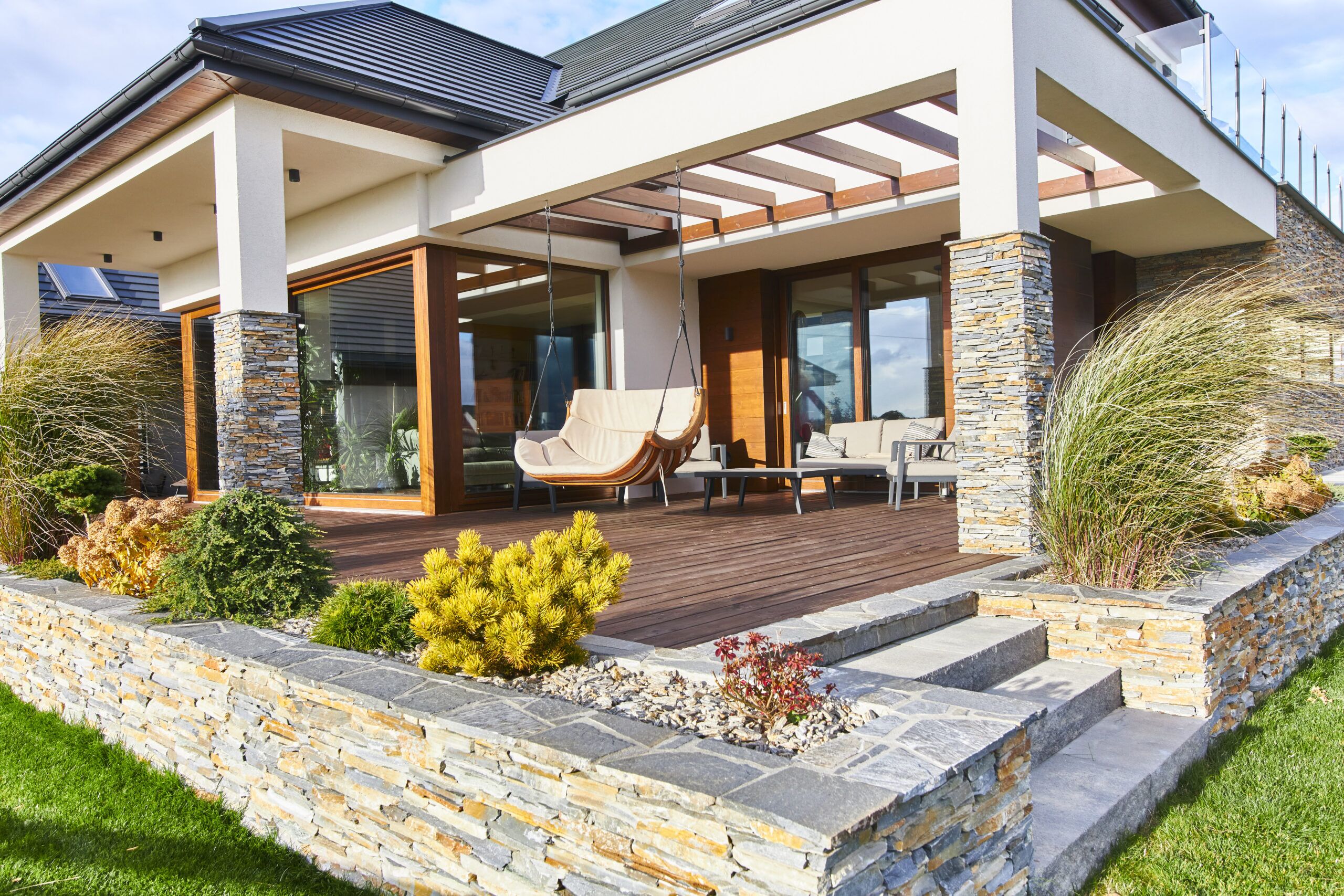 duży drewniany taras z pergolą i huśtawką oraz widokiem na góry to strefa relaksu w projekcie dużego nowoczesnego domu w Nowym Sączu