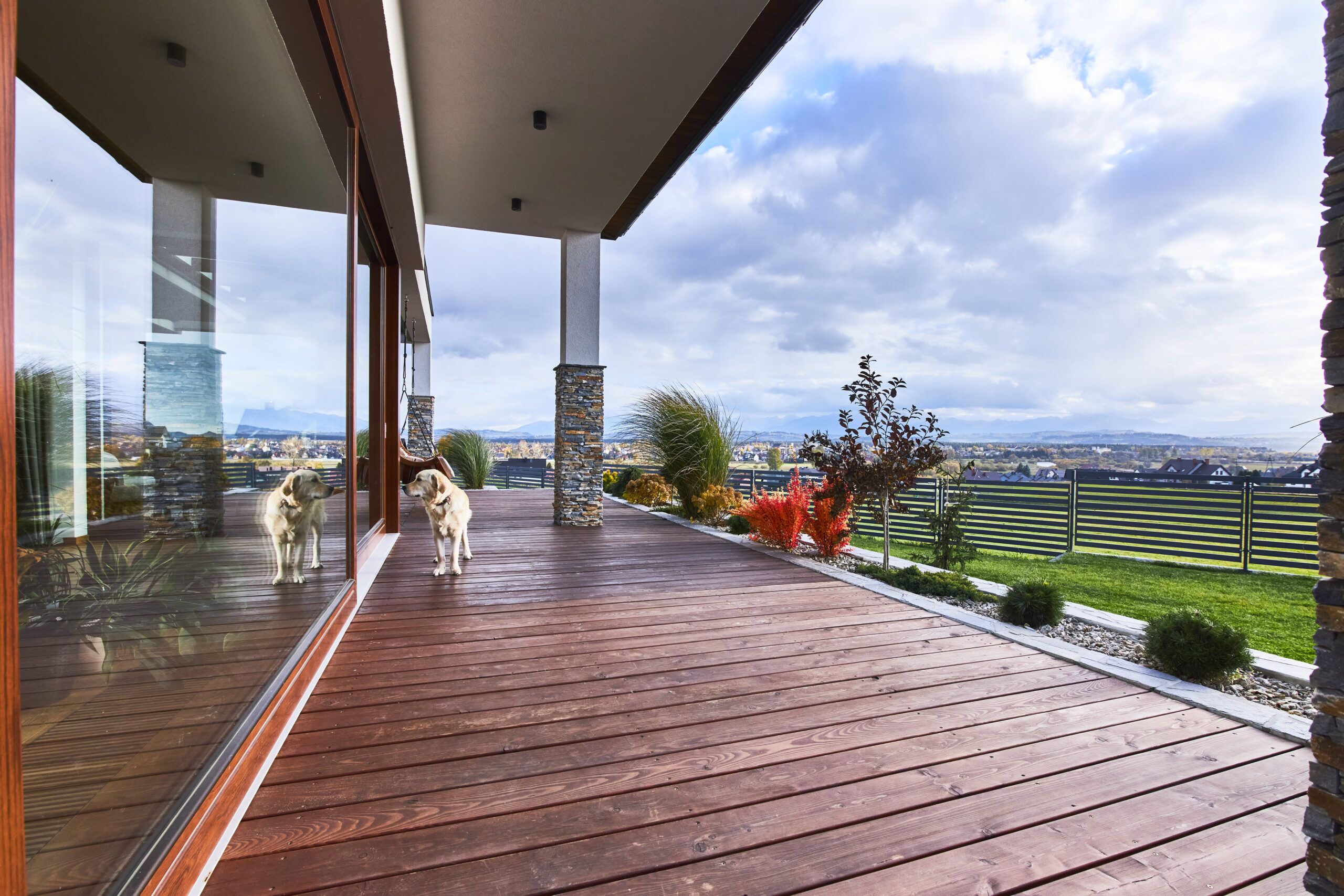 Duży taras z naturalnego drewna i łupek na elewacji oraz duże przesuwne okno drewniano aluminiowe to projekt nowoczesnej rezydencji z widokiem na góry w Nowym Sączu