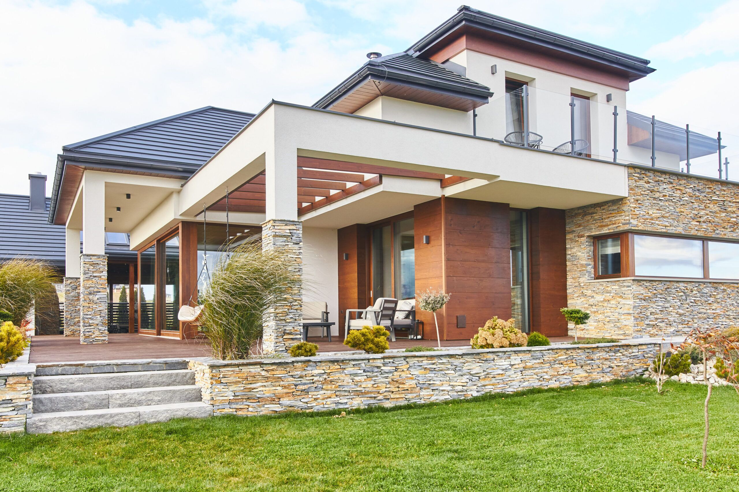 połączenie kamienia łupek z drewnem elewacyjnym to pomysł na aranżacje dużych tarasów w projekcie dużego domu w Nowym Sączu